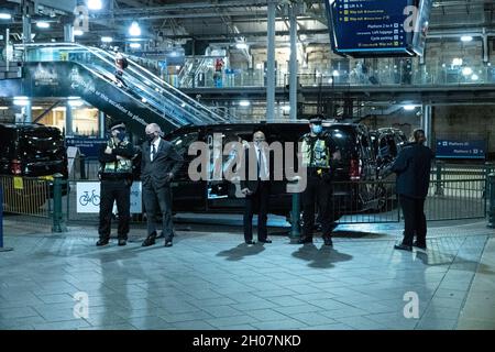 Edimburgo, stazione ferroviaria di Waverley, Scozia, Regno Unito, 11 ottobre 2021: Il re della Malesia (Abdullah di Pahang) (indossando un cappello, occhiali e una copertura blu) circondato dal suo entourage e team di sicurezza, arriva alla stazione ferroviaria di Waverley a Edimburgo. Una flotta di mini bus in attesa, per prendere il re e il suo entourage off. La British Transport Police ha fornito anche una maggiore sicurezza. Credit Barry Nixon/Alamy Live News Foto Stock