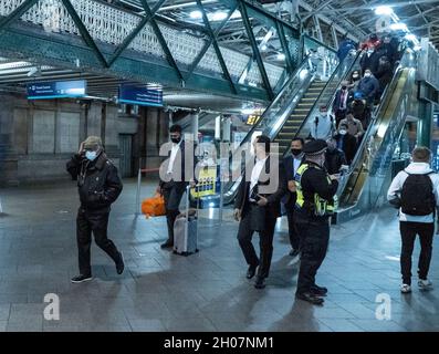 Edimburgo, stazione ferroviaria di Waverley, Scozia, Regno Unito, 11 ottobre 2021: Il re della Malesia (Abdullah di Pahang) (indossando un cappello, occhiali e una copertura blu) circondato dal suo entourage e team di sicurezza, arriva alla stazione ferroviaria di Waverley a Edimburgo. Una flotta di mini bus in attesa, per prendere il re e il suo entourage off. La British Transport Police ha fornito anche una maggiore sicurezza. Credit Barry Nixon/Alamy Live News Foto Stock