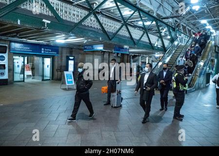 Edimburgo, stazione ferroviaria di Waverley, Scozia, Regno Unito, 11 ottobre 2021: Il re della Malesia (Abdullah di Pahang) (indossando un cappello, occhiali e una copertura blu) circondato dal suo entourage e team di sicurezza, arriva alla stazione ferroviaria di Waverley a Edimburgo. Una flotta di mini bus in attesa, per prendere il re e il suo entourage off. La British Transport Police ha fornito anche una maggiore sicurezza. Credit Barry Nixon/Alamy Live News Foto Stock