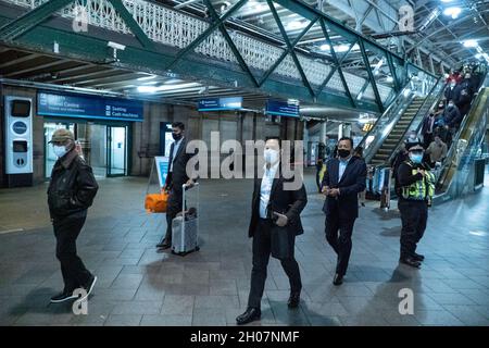 Edimburgo, stazione ferroviaria di Waverley, Scozia, Regno Unito, 11 ottobre 2021: Il re della Malesia (Abdullah di Pahang) (indossando un cappello, occhiali e una copertura blu) circondato dal suo entourage e team di sicurezza, arriva alla stazione ferroviaria di Waverley a Edimburgo. Una flotta di mini bus in attesa, per prendere il re e il suo entourage off. La British Transport Police ha fornito anche una maggiore sicurezza. Credit Barry Nixon/Alamy Live News Foto Stock