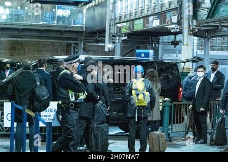 Edimburgo, stazione ferroviaria di Waverley, Scozia, Regno Unito, 11 ottobre 2021: Il re della Malesia (Abdullah di Pahang) (indossando un cappello, occhiali e una copertura blu) circondato dal suo entourage e team di sicurezza, arriva alla stazione ferroviaria di Waverley a Edimburgo. Una flotta di mini bus in attesa, per prendere il re e il suo entourage off. La British Transport Police ha fornito anche una maggiore sicurezza. Credit Barry Nixon/Alamy Live News Foto Stock