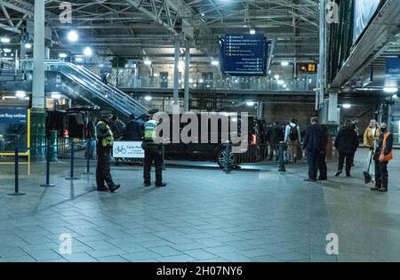 Edimburgo, stazione ferroviaria di Waverley, Scozia, Regno Unito, 11 ottobre 2021: Il re della Malesia (Abdullah di Pahang) (indossando un cappello, occhiali e una copertura blu) circondato dal suo entourage e team di sicurezza, arriva alla stazione ferroviaria di Waverley a Edimburgo. Una flotta di mini bus in attesa, per prendere il re e il suo entourage off. La British Transport Police ha fornito anche una maggiore sicurezza. Credit Barry Nixon/Alamy Live News Foto Stock