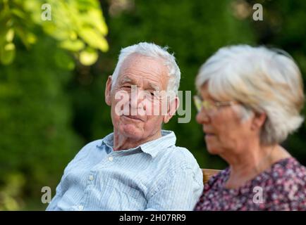 Coppia anziana seduta in giardino e parlare in estate Foto Stock