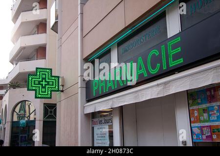 Farmacia francese con cartello verde neon - Pharmacie - di fronte a un edificio. Nizza, Francia - 27 settembre 2021. Foto Stock