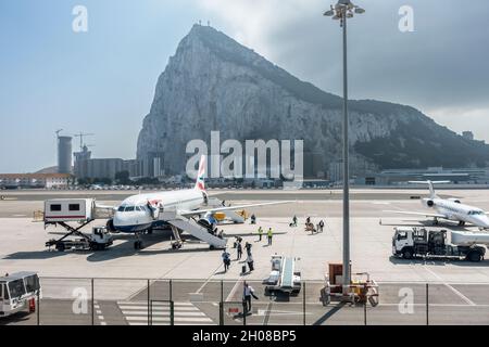 Pssgers (indossare maschere) lasciando un Airbus British Airways A320-232 che è appena arrivato ed è sul grembiule all'aeroporto di Gibilterra. Una Eastern Airway Foto Stock