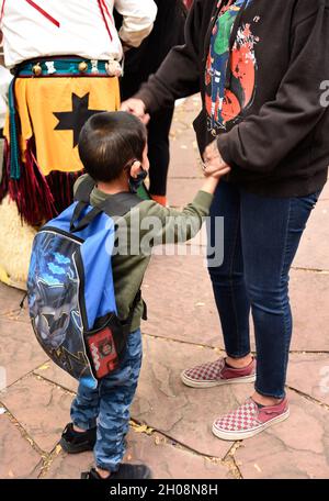 Una donna dei nativi americani e il suo giovane figlio tengono le mani in attesa dell'inizio della celebrazione della Giornata dei popoli indigeni a Santa Fe, New Mexico. Foto Stock