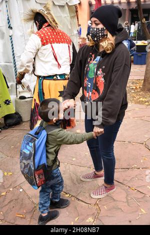 Una donna dei nativi americani e il suo giovane figlio tengono le mani in attesa dell'inizio della celebrazione della Giornata dei popoli indigeni a Santa Fe, New Mexico. Foto Stock