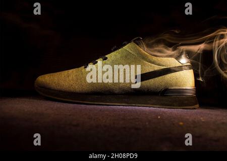 Primo piano di un'elegante sneaker gialla con fumo in uscita. Foto Stock