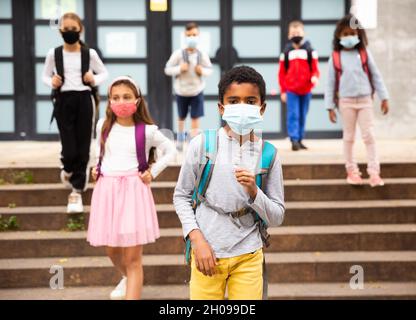 Scolboy afro-americano Tween in maschera protettiva andare a scuola Foto Stock