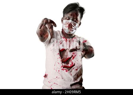 Spaventoso zombie nella maschera facciale con sangue e ferita sul suo corpo in piedi isolato su sfondo bianco Foto Stock