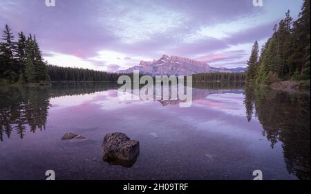 Tranquilla e colorata alba con montagna dominante che si riflette sulla superficie di laghi fermi, Banff National Park, Canada Foto Stock