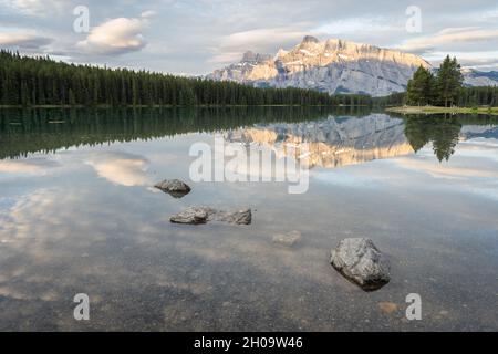 Tranquilla e colorata alba con montagna dominante che si riflette sulla superficie del lago fermo, Banff National Park, Canada Foto Stock