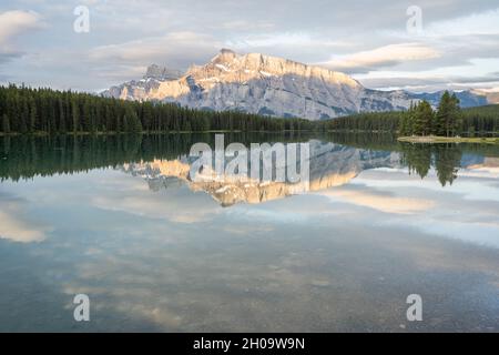 Tranquilla e colorata alba con montagna dominante che si riflette sulla superficie del lago fermo, Banff National Park, Canada Foto Stock