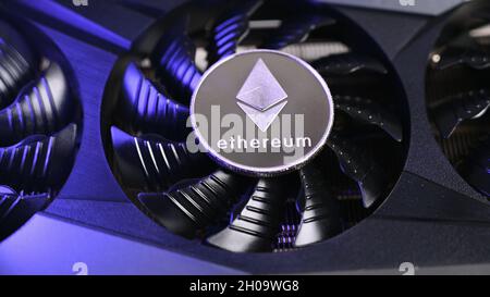 Primo piano della moneta Ethereum su una scheda video nera illuminata da luce blu. Il concetto di estrazione di Ethereum Foto Stock