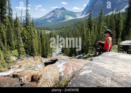 Donna escursionista che gode di vista sulla splendida valle alpina con montagne sullo sfondo, Banff National Park, Canada Foto Stock