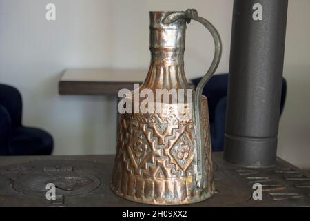 pentola di rame intagliata molto vecchia usata per riscaldare l'acqua su una stufa Foto Stock