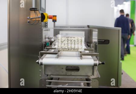 Primo piano degli alimenti in scatole di plastica sulla macchina confezionatrice dello stabilimento Foto Stock