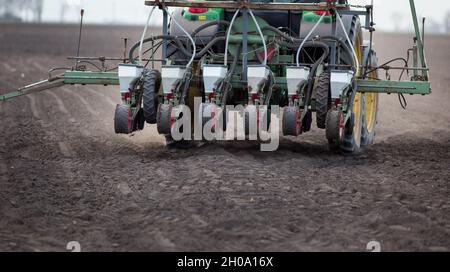 Vista posteriore del trattore con seminatrice che guida su campo in primavera Foto Stock