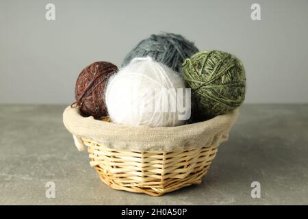 Palle di filo multicolore in un cestino di vimini su sfondo grigio chiaro. Foto Stock