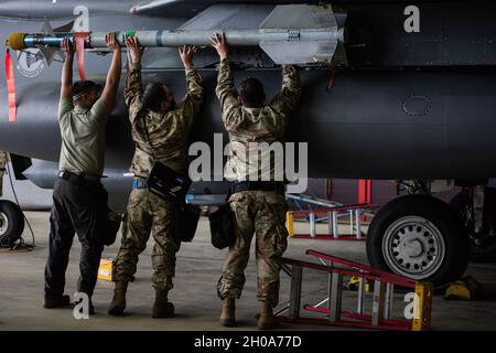 Gli aerei della forza aerea degli Stati Uniti assegnati alla 492a unità di manutenzione dell'aeromobile lavorano insieme per caricare un missile su un'aquila di Strike F-15E durante la competizione Weapons Load Crew of the Year alla Royal Air Force Lakenheath, Inghilterra, 5 gennaio 2021. Le squadre lavorano insieme per garantire che l'aeromobile sia sicuro per il caricamento, che le bombe e i lanciatori siano configurati correttamente e che le munizioni siano ispezionate per soddisfare i requisiti della missione. Foto Stock