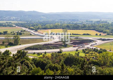 Veicoli su un cantiere stradale. Autocarri pesanti, escavatori e rulli stradali allineati alla fine della giornata, ad ovest di Sopron, Ungheria Foto Stock