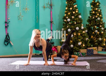 Bella donna e una ragazza vanno in per gli sport a Natale vicino ad un albero di Natale decorato, sport e vacanza. Foto di alta qualità. Foto Stock
