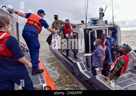 Guardia costiera degli Stati Uniti Lt. CMdR. Jason McCarthey, funzionario operativo della pietra USCGC (WMSL 758), scambia regali con i membri della Guyana Coast Guard al largo della costa della Guyana il 9 gennaio 2021. Dopo aver stipulato un accordo bilaterale il 18 settembre 2020, la Guardia Costiera degli Stati Uniti e la Guyana Coast Guard hanno completato il loro primo esercizio di addestramento cooperativo per la lotta al traffico marittimo illecito. Foto Stock