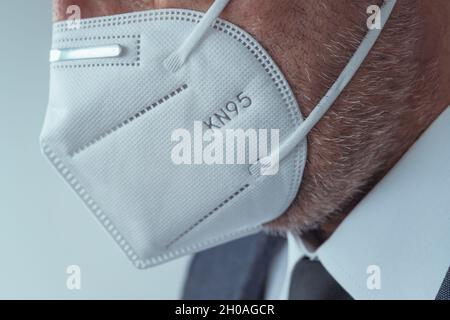 Elegante uomo d'affari che indossa maschera respiratoria protettiva KN95 durante le pandemie di Covid-19, fuoco selettivo Foto Stock