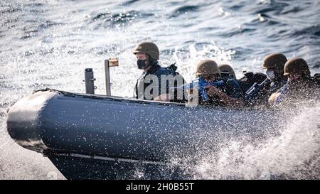 I marinai effettuano “manovre a ferro di cavallo” in una barca gonfiabile a scafo rigido prima di salire a bordo del cacciatorpediniere missilistico guidato di classe Arleigh Burke USS John S. McCain (DDG 56) durante una visita, bordo, ricerca e sequestro (VBSS). McCain è assegnato al Destroyer Squadron (DESRON) 15, il più grande DESRON schierato in avanti della Marina e la principale forza di superficie della 7a flotta statunitense. Foto Stock