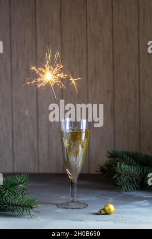 Bicchiere di Natale con champagne e scintillanti su un tavolo in pietra grigia. Natale concetto di vacanza con abete Foto Stock