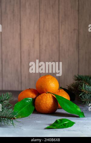 Festosa piramide di mandarini con foglie e rami di albero di Natale su un tavolo di pietra grigia. Spazio di copia Foto Stock