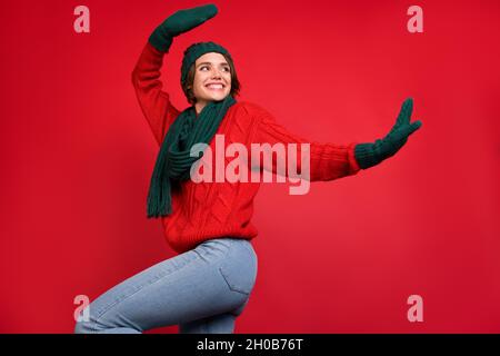 Foto ritratto giovane donna che balla a festa in sciarpa mittens guardando copyspace isolato vibrante colore rosso sfondo Foto Stock