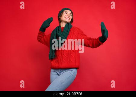 Foto ritratto giovane donna in cerca di copyspace in sciarpa mittens isolato vibrante colore rosso sfondo Foto Stock