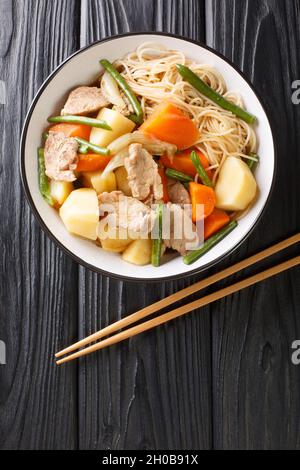 Nikujaga Ricetta maiale e patate stufati in saporito salsa di soia a base di Dashi Broth primo piano in ciotola su uno sfondo nero verticale vista dall'alto Foto Stock