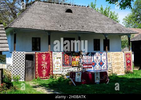 Bucarest, Romania - 25 Aprile 2021: Vecchia casa rumena tradizionale circondata da molti alberi antichi e erba verde in Dimitrie Gusti National Village Mu Foto Stock
