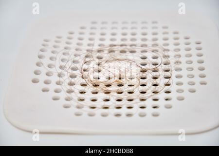 Quando si scarica l'acqua nel lavandino, i capelli sulla griglia di plastica del raccoglitore Foto Stock