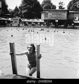 Eine Frau steigt aus dem Schwimmbecken eines Mineralbads, Deutschland 1930er Jahre. Una donna off arrampicata di una piscina termale, Germania 1930s. Foto Stock