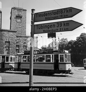 Wegweiser nach Freudenstadt, Böblingen, Tübingen und Waldenbuch vor einer Strassenbahn der Linie 6 am Hauptbahnhof Stoccarda, Deutschland 1930er Jahre. Guidepost a Freudenstadt, Boeblingen, Tuebingen e Waldenbuch davanti a un tram di linea n. 6 alla stazione centrale di Stoccarda, Germania 1930s. Foto Stock