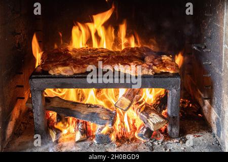 Bistecche di maiale preparazione su una lastra di pietra grill Foto Stock