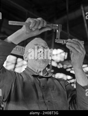 Arbeiter in einer Fabrikhalle bei Mercedes Benz a Stuttgart, Deutschland 1930er Jahre. Lavoratore in una fabbrica di Mercedes Benz a Stoccarda, Germania anni trenta. Foto Stock