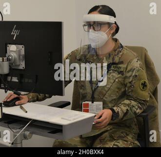 Illinois Army National Guard Medic SPC. Lynnette Banvelos di Addison, Illinois, inserisce le risposte alle domande di screening della vaccinazione nella rete del Dipartimento sanitario della contea di Cook prima di somministrare un vaccino ad un membro della comunità locale del Centro sanitario della contea di Cook. I medici dell'esercito ricevono circa quattro mesi di addestramento intensivo nelle mansioni mediche a Fort Sam Houston, Texas, compreso la somministrazione delle vaccinazioni. Dopo la loro formazione iniziale, i medici sono tenuti a ri-certificare periodicamente. In Illinois, i medici sono certificati dallo stato a livello di EMT, ma il Foto Stock