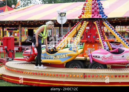 Un addetto al fairground controlla il divertente giro in aeroplano dei bambini alla fiera Leatherhead del 2021 luglio Foto Stock