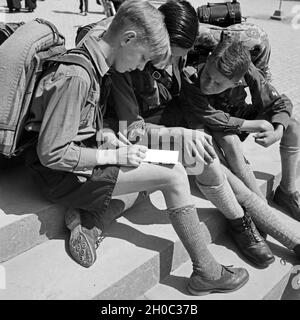 Drei Hitlerjungen schreiben eine Postkarte von einer Wanderung, Deutschland 1930er Jahre. Tre giovani Hitler scrivendo una cartolina da un viaggio errante, Germania 1930s. Foto Stock