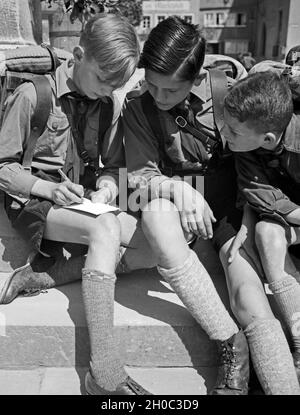 Drei Hitlerjungen schreiben eine Postkarte von einer Wanderung, Deutschland 1930er Jahre. Tre giovani Hitler scrivendo una cartolina da un viaggio errante, Germania 1930s. Foto Stock