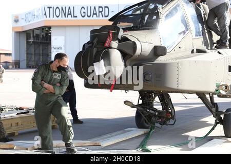 I membri della 161a Air Refying Wing della Guardia Nazionale dell'Arizona, della Royal Air Force e della Boeing Company caricano un elicottero AH-64 Apache in una Royal Air Force C-17 Globemaster III, presso la Goldwater Air National Guard base di Phoenix, Arizona, 21 gennaio 2021. Il 161° è stato contattato dall'ufficio del programma di vendita militare estero Apache dell'esercito degli Stati Uniti per aiutare a caricare gli elicotteri da attacco su aeromobili C-17 per la spedizione nel Regno Unito, grazie al suo spazio sicuro per la rampa del progetto, e specialisti qualificati del trasporto aereo in grado di trattare carichi aerei complessi garantendo la sicurezza del volo durante il trasporto aereo. Foto Stock