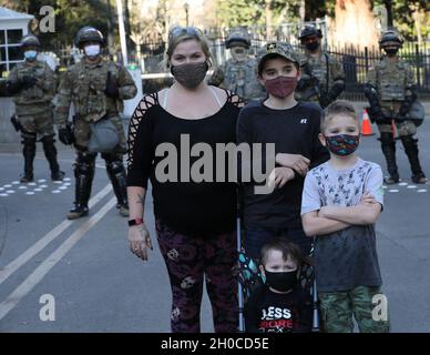 I bambini nativi di Sacramento Melissa Bain e Savin posano di fronte ai Guardia Nazionale dell'Esercito della California dalla 270th Military Police Company, 185th Military Police Battaglione, 49th Military Police Brigade, 20 gennaio 2021 durante l'inaugurazione del Presidente Biden. I civili passeggiavano davanti al campidoglio dello stato e le truppe li obbligavano felicemente a fare una richiesta fotografica. Le forze di guardia CAL sono state attivate per proteggere e difendere vite, proprietà e diritti di tutti i californiani. Foto Stock