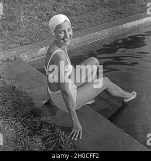 Eine junge Frau beim Sonnenbad am Schwimmbecken, Deutschland 1930 Jahre. Una giovane donna in posa mentre prendisole in piscina, Germania anni trenta. Foto Stock