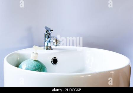 Lavello rotondo bianco in ceramica con dispenser verde per pompetta sapone in ceramica. Pulizia sfondo bianco. Spazio di copia. Foto Stock