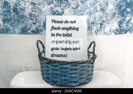 Promemoria amichevole wc segno nel cestino blu con il testo 'si prega di non sciacquare nulla nel bagno - soprattutto non la tua speranza e sogni' Foto Stock
