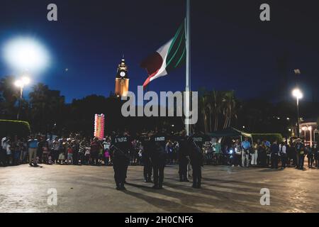 Merida, Messico: 28 ottobre 2018 - uomini di polizia che abbassano e rimuovono la bandiera messicana davanti agli spettatori sulla 'Plaza Grande' Foto Stock